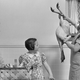 1940s mother proudly holds up plucked turkey to show children